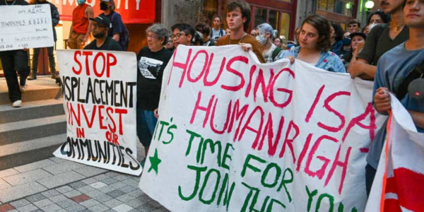 Protesters holding up a sign that reads “Housing is a human right, it's time for you to join the fight” © Joe Piette/Flickr
